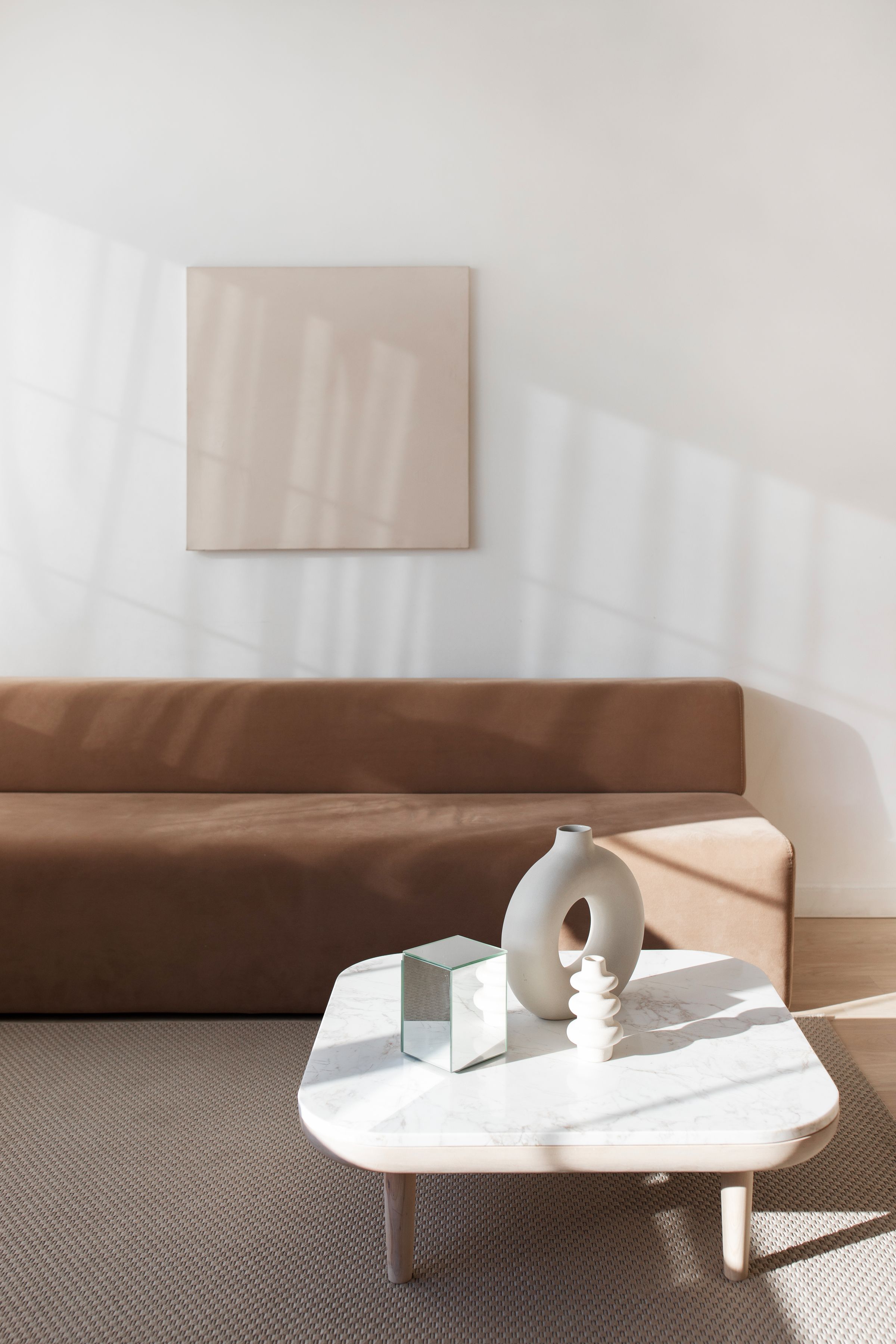 Minimal designer living room in daylight with a marble table and sculptural objects.